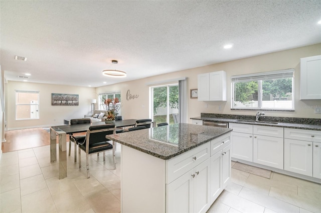 16828 N Gold Star Ct, Clermont, FL 34714 - kitchen with healthy amount of natural light, a center island, dark stone countertops, dishwasher, and a textured ceiling
