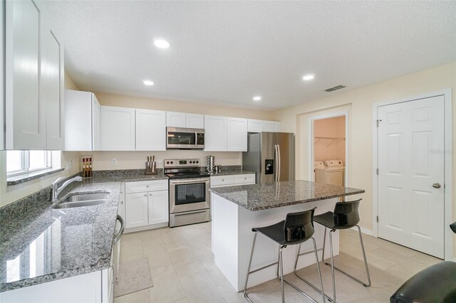 16828 N Gold Star Ct, Clermont, FL 34714 - kitchen featuring stainless steel appliances, separate washer and dryer, white cabinets, dark stone countertops, and recessed lighting
