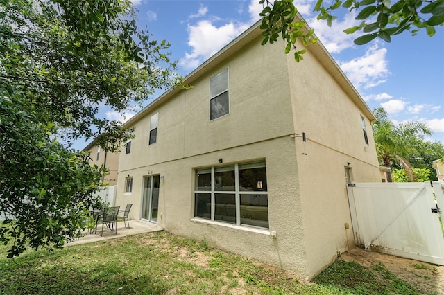 16828 N Gold Star Ct, Clermont, FL 34714 - back of property with stucco siding, a patio, and a gate