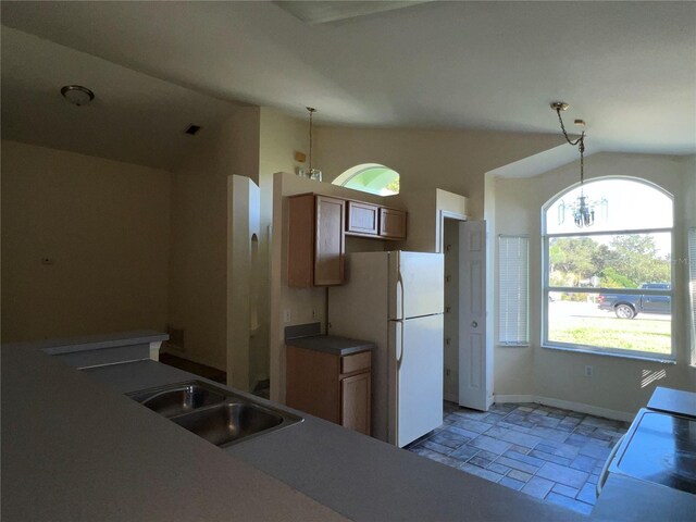 103 Thornbush Pkwy, Davenport, FL 33837 - kitchen with freestanding refrigerator, light stone finish flooring, hanging light fixtures, a chandelier, and brown cabinetry