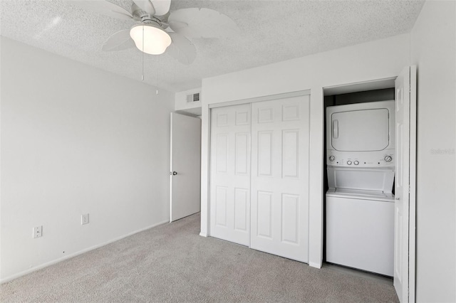 14800 Walsingham Rd Unit 1215, Largo, FL 33774 - unfurnished bedroom featuring stacked washing machine and dryer, carpet floors, a textured ceiling, a closet, and a ceiling fan