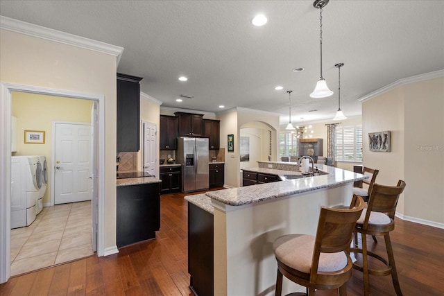 19409 Wingrove Ln, Lutz, FL 33558 - kitchen featuring stainless steel fridge, independent washer and dryer, ornamental molding, arched walkways, and dark wood finished floors
