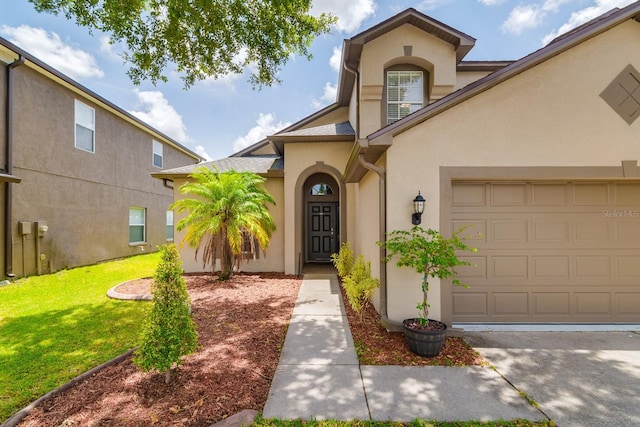 18508 Merseyside Loop, Land O Lakes, FL 34638 - view of exterior entry with stucco siding, a lawn, and an attached garage