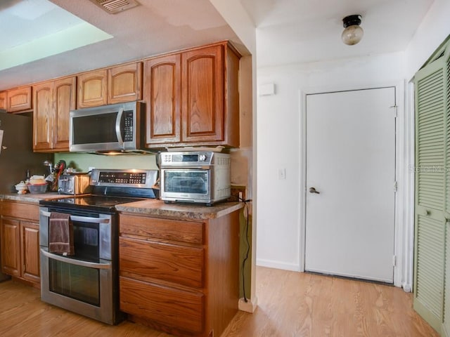 1610 Sanderling Ct, Brandon, FL 33511 - kitchen with stainless steel appliances, light wood finished floors, and brown cabinetry