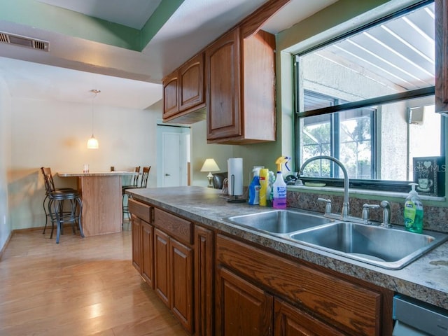 1610 Sanderling Ct, Brandon, FL 33511 - kitchen with hanging light fixtures, light wood-type flooring, dishwasher, brown cabinets, and dark countertops