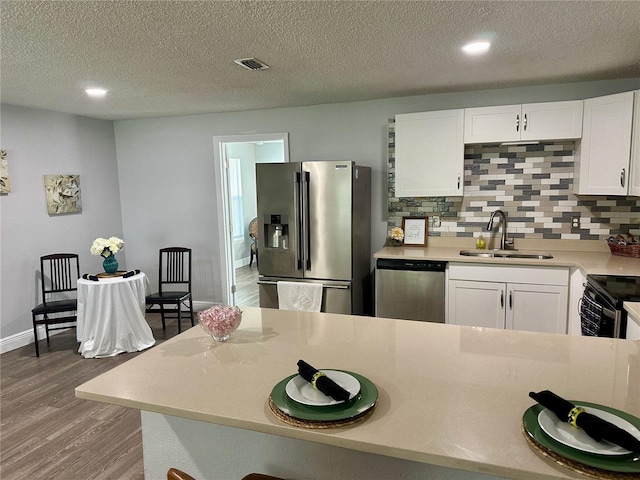 7301 Mitchell Ranch Rd, New Port Richey, FL 34655 - kitchen with stainless steel appliances, wood finished floors, white cabinets, decorative backsplash, and light countertops