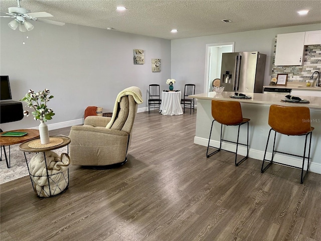 7301 Mitchell Ranch Rd, New Port Richey, FL 34655 - kitchen featuring stainless steel refrigerator with ice dispenser, a kitchen bar, light countertops, dark wood finished floors, and a textured ceiling