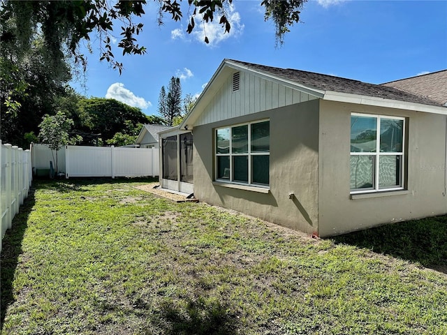 7301 Mitchell Ranch Rd, New Port Richey, FL 34655 - rear view of house with a fenced backyard, stucco siding, a sunroom, and roof with shingles