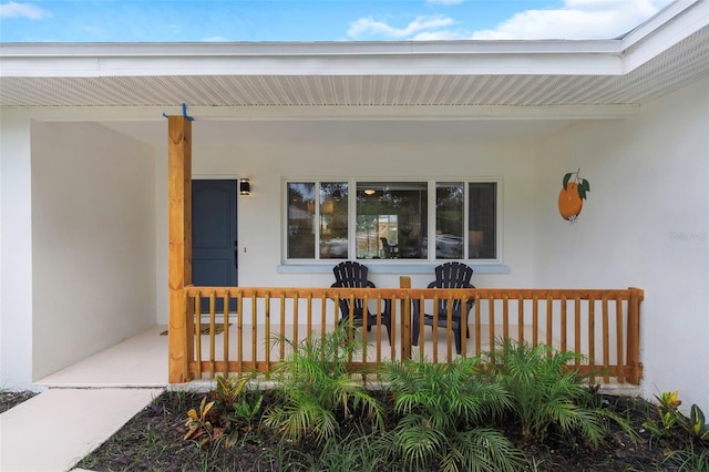 245 Grove Cir N, Dunedin, FL 34698 - doorway to property with covered porch and stucco siding