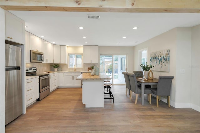 245 Grove Cir N, Dunedin, FL 34698 - kitchen with appliances with stainless steel finishes, a kitchen bar, recessed lighting, decorative backsplash, and a kitchen island