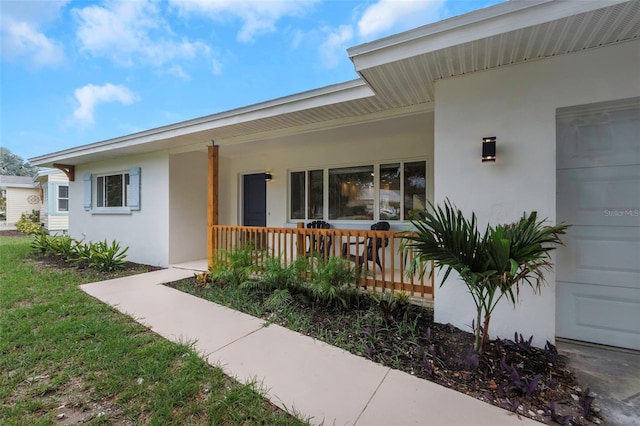 245 Grove Cir N, Dunedin, FL 34698 - property entrance featuring stucco siding, a porch, and an attached garage