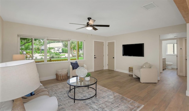 245 Grove Cir N, Dunedin, FL 34698 - living room with a ceiling fan, light wood-style flooring, and plenty of natural light