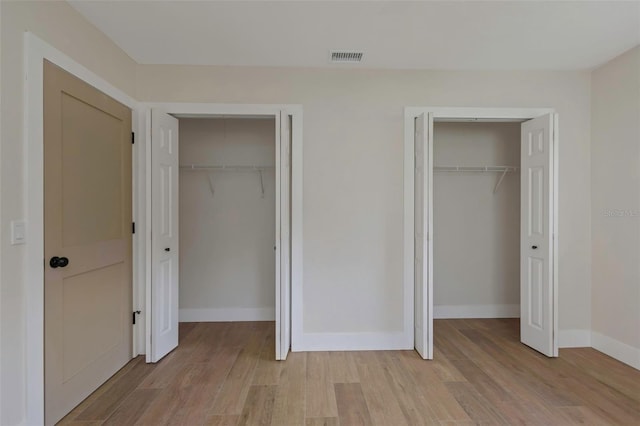 245 Grove Cir N, Dunedin, FL 34698 - unfurnished bedroom with two closets and light wood finished floors