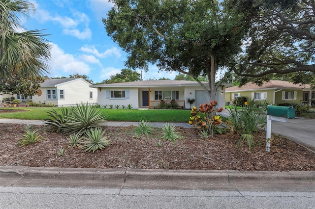 245 Grove Cir N, Dunedin, FL 34698 - single story home with a front yard, stucco siding, an attached garage, and a porch