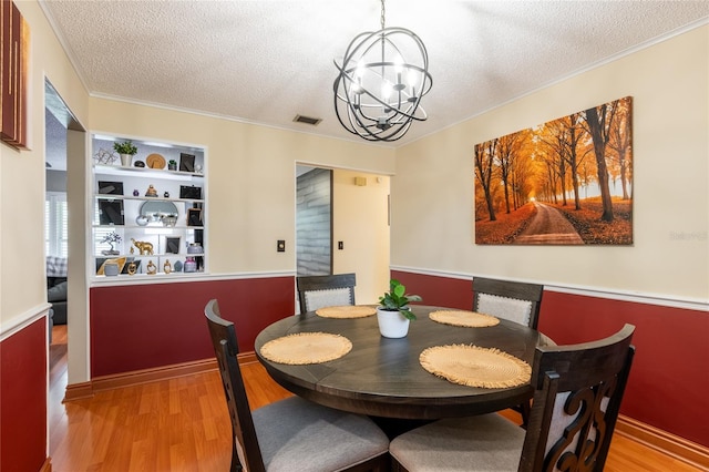 616 Pawn Way, Seffner, FL 33584 - dining area with a textured ceiling, a chandelier, light wood-style floors, and ornamental molding