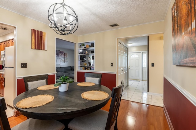 616 Pawn Way, Seffner, FL 33584 - dining room featuring light wood-style floors, a textured ceiling, a chandelier, and crown molding