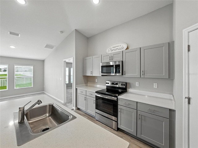 12931 Twin Bridges Dr, Riverview, FL 33579 - kitchen featuring stainless steel appliances, gray cabinets, vaulted ceiling, light countertops, and light wood finished floors