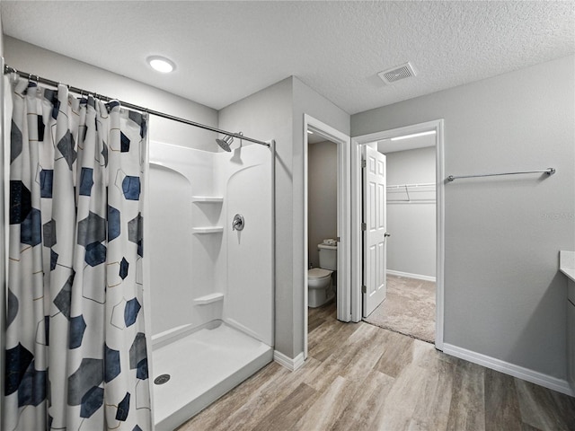 12931 Twin Bridges Dr, Riverview, FL 33579 - bathroom with wood finished floors, a shower stall, a walk in closet, a textured ceiling, and vanity