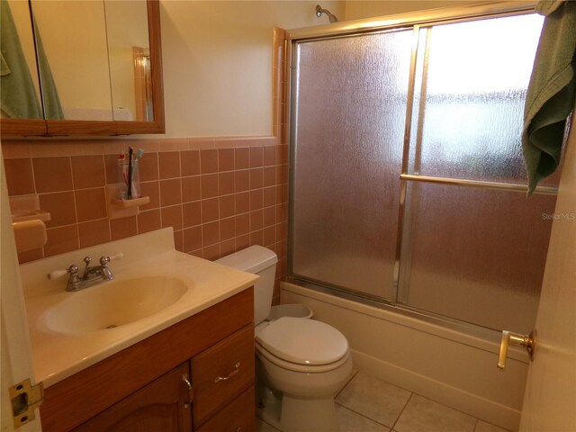 2239 Curtis Dr S, Clearwater, FL 33764 - full bath featuring vanity, shower / bath combination with glass door, tile patterned floors, wainscoting, and tile walls