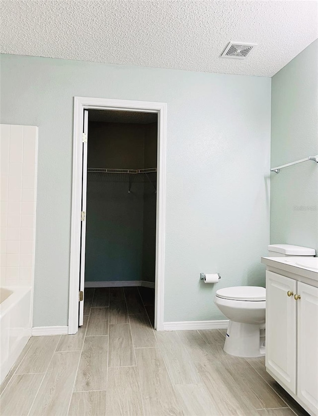 1990 Eclipse Dr, Middleburg, FL 32068 - bathroom featuring vanity, wood finished floors, a textured ceiling, and a spacious closet