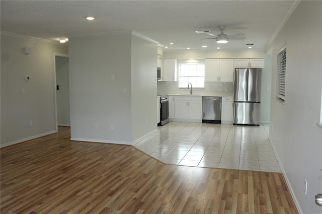 6144 Elmhurst Dr, New Port Richey, FL 34653 - kitchen featuring stainless steel appliances, a ceiling fan, ornamental molding, white cabinets, and tasteful backsplash