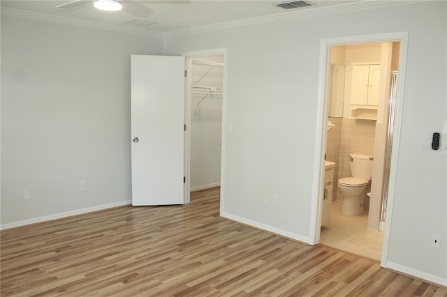 6144 Elmhurst Dr, New Port Richey, FL 34653 - unfurnished bedroom with wood finished floors, ornamental molding, ensuite bath, a closet, and a spacious closet