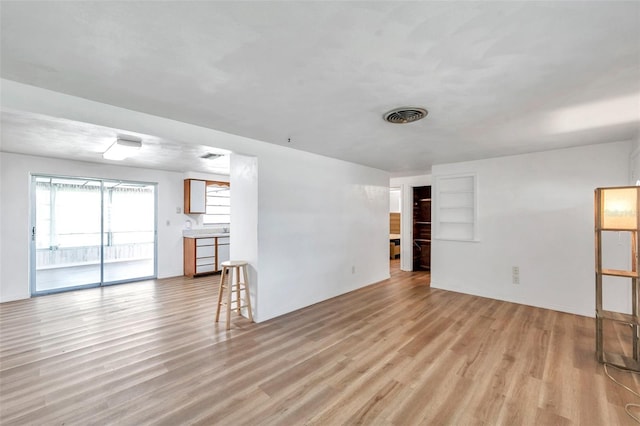 4911 Bartelt Rd, Holiday, FL 34690 - unfurnished living room featuring light wood-type flooring and built in features