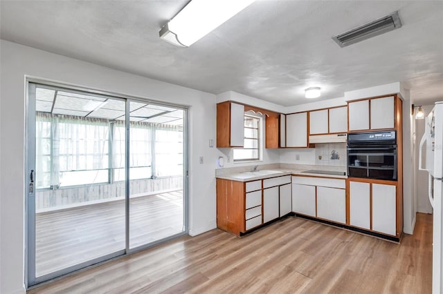 4911 Bartelt Rd, Holiday, FL 34690 - kitchen featuring black appliances, light countertops, light wood-style flooring, and under cabinet range hood