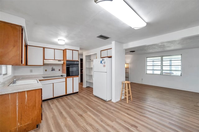4911 Bartelt Rd, Holiday, FL 34690 - kitchen featuring black appliances, under cabinet range hood, light wood-style floors, light countertops, and open floor plan