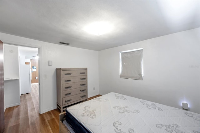 4911 Bartelt Rd, Holiday, FL 34690 - bedroom featuring freestanding refrigerator and light wood-style flooring