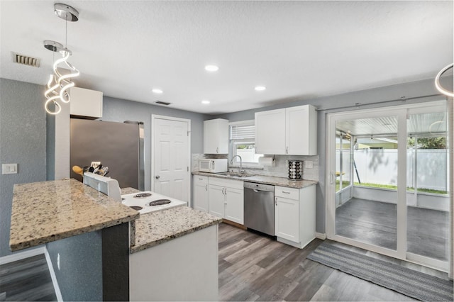 8897 54th St N, Pinellas Park, FL 33782 - kitchen featuring appliances with stainless steel finishes, dark wood-style flooring, white cabinetry, a peninsula, and recessed lighting