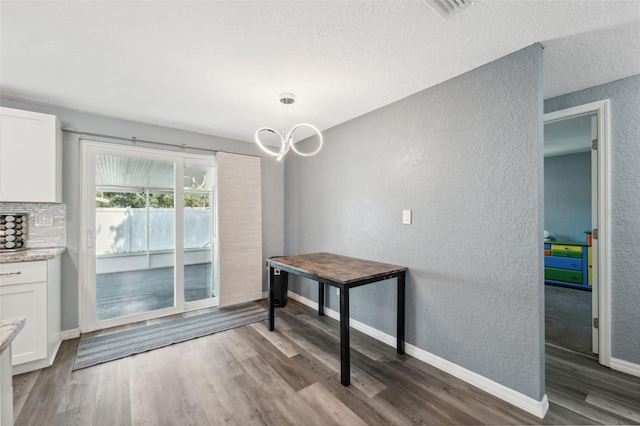 8897 54th St N, Pinellas Park, FL 33782 - unfurnished dining area with a textured wall, dark wood-style flooring, a chandelier, and a textured ceiling