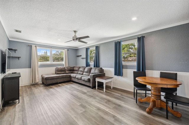 8897 54th St N, Pinellas Park, FL 33782 - living room with a textured ceiling, a wainscoted wall, light wood finished floors, ceiling fan, and ornamental molding