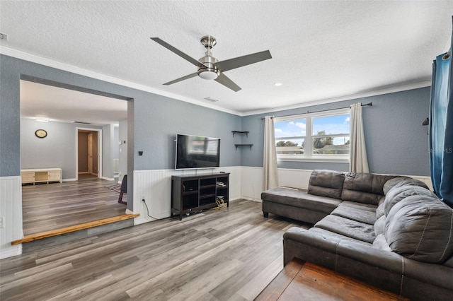8897 54th St N, Pinellas Park, FL 33782 - living room with a textured ceiling, wood finished floors, ornamental molding, a ceiling fan, and wainscoting
