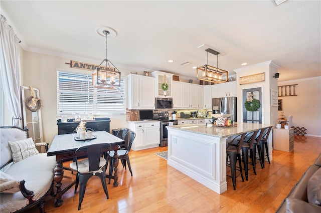 5102 Pheasant Woods Dr, Lutz, FL 33558 - kitchen featuring appliances with stainless steel finishes, white cabinetry, crown molding, a breakfast bar area, and light wood-style flooring