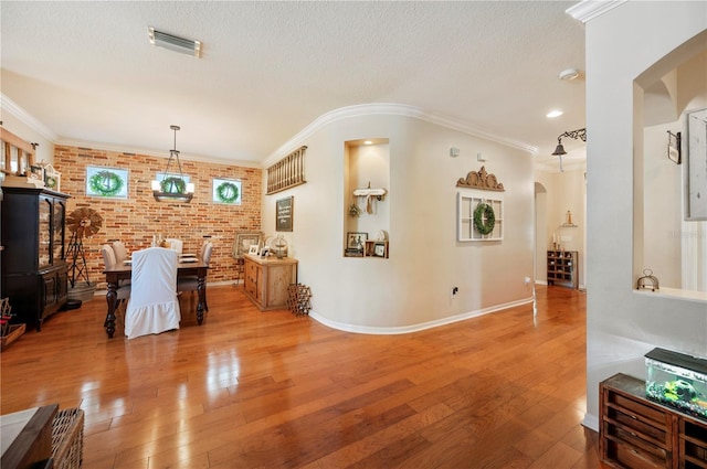 5102 Pheasant Woods Dr, Lutz, FL 33558 - dining room featuring arched walkways, brick wall, wood-type flooring, a textured ceiling, and crown molding
