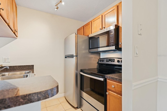 302 Lake Parsons Grn Unit 104, Brandon, FL 33511 - kitchen featuring stainless steel appliances, light tile patterned flooring, dark countertops, and a textured ceiling
