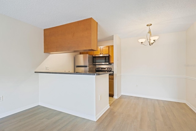 302 Lake Parsons Grn Unit 104, Brandon, FL 33511 - kitchen with stainless steel appliances, light wood-type flooring, a chandelier, brown cabinetry, and a textured ceiling