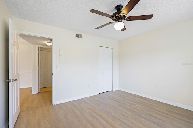 302 Lake Parsons Grn Unit 104, Brandon, FL 33511 - unfurnished bedroom featuring light wood-style floors, a textured ceiling, a closet, and a ceiling fan