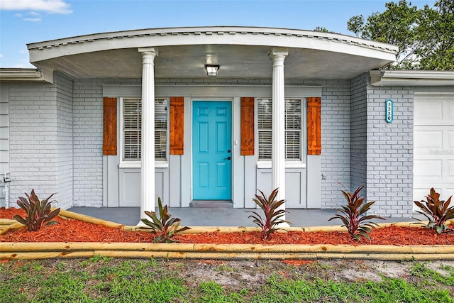 3330 Rock Royal Dr, Holiday, FL 34691 - doorway to property featuring brick siding, a garage, and a porch