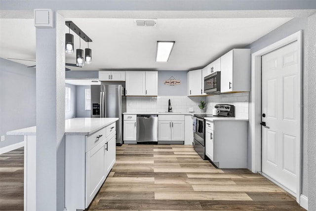3330 Rock Royal Dr, Holiday, FL 34691 - kitchen with appliances with stainless steel finishes, light countertops, light wood-style floors, backsplash, and white cabinets