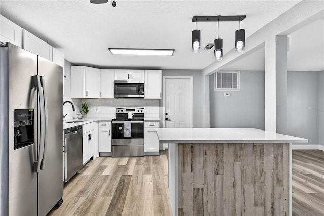 3330 Rock Royal Dr, Holiday, FL 34691 - kitchen featuring appliances with stainless steel finishes, light wood-type flooring, light countertops, white cabinetry, and decorative backsplash