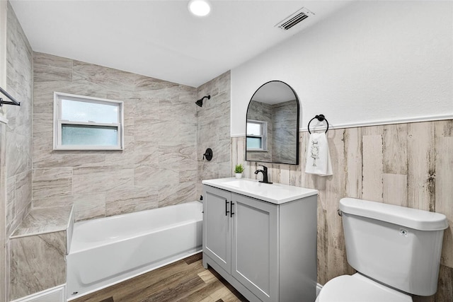 3330 Rock Royal Dr, Holiday, FL 34691 - full bath featuring vanity, shower / bathtub combination, tile walls, and wood finished floors
