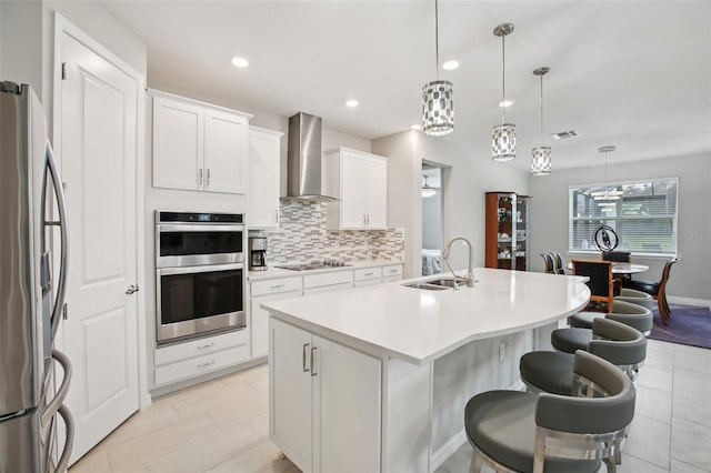 9107 Rally Spring Loop, Wesley Chapel, FL 33545 - kitchen featuring wall chimney range hood, stainless steel appliances, a kitchen island with sink, backsplash, and light countertops