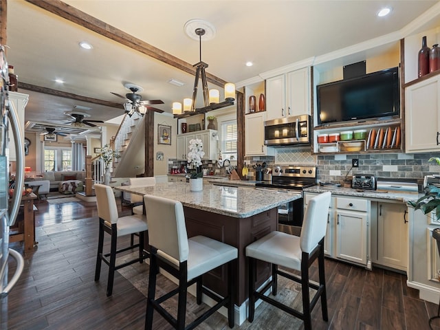 2504 W N A St Unit A, Tampa, FL 33609 - kitchen featuring appliances with stainless steel finishes, a ceiling fan, a kitchen breakfast bar, tasteful backsplash, and light stone countertops