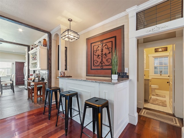 2504 W N A St Unit A, Tampa, FL 33609 - bar with dark wood-style flooring, crown molding, arched walkways, decorative backsplash, and pendant lighting