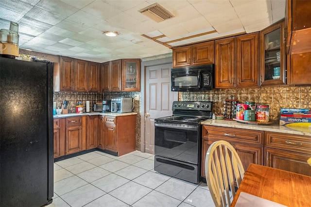 5651 6th St, Zephyrhills, FL 33542 - kitchen featuring black appliances, light countertops, decorative backsplash, light tile patterned flooring, and glass insert cabinets