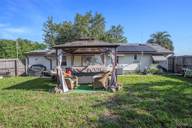 5651 6th St, Zephyrhills, FL 33542 - rear view of house with stucco siding, roof mounted solar panels, a fenced backyard, and a gazebo