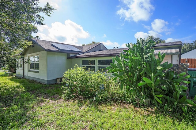 5651 6th St, Zephyrhills, FL 33542 - back of property featuring concrete block siding, solar panels, and a shingled roof