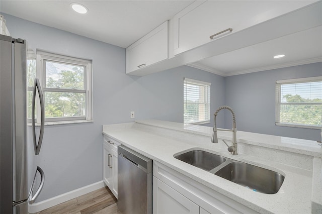 2525 W Bay Dr Unit A46, Largo, FL 33770 - kitchen with appliances with stainless steel finishes, healthy amount of natural light, light wood-style flooring, white cabinets, and ornamental molding